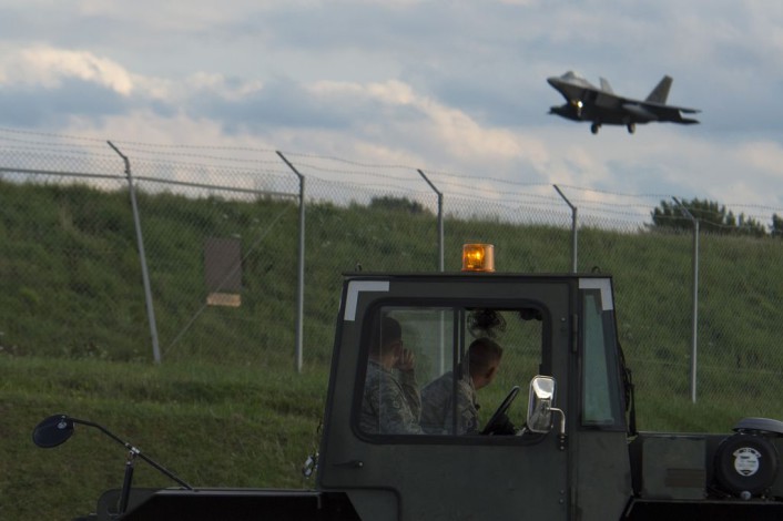 Two Airmen watch as an F-22 Raptor fighter aircraft assigned to the 95th Fighter Squadron at Tyndall Air Force Base, Fla., prepares to land at Spangdahlem Air Base, Germany, Aug. 28, 2015. The U.S. Air Force deployed four F-22s, one C-17 Globemaster III and more than 50 Airmen to Spangdahlem in support of the first F-22 European training deployment. The inaugural F-22 training deployment to Europe is funded by the European Reassurance Initiative, a $1 billion pledge announced by President Obama in March 2014. (U.S. Air Force photo by Airman 1st Class Luke Kitterman/Released)