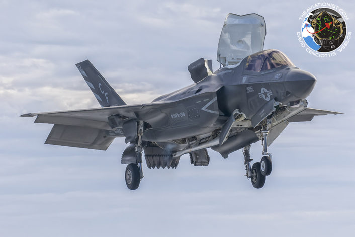 F-35B of USMC VMFA-211 hovers aside the USS America as it prepares for a vertical landing on deck during the integrated USN/USMC proof of concept demonstration November 19, 2016.